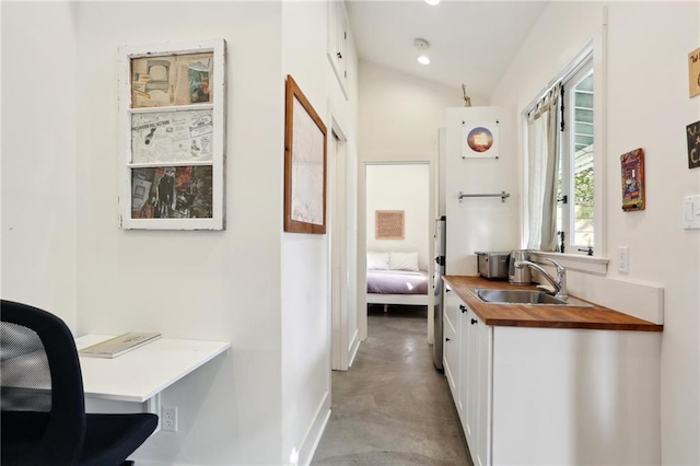 corridor with sink and lofted ceiling