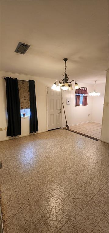 unfurnished room featuring an inviting chandelier