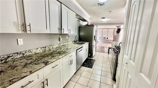 kitchen featuring white cabinetry, light stone counters, appliances with stainless steel finishes, and ornamental molding