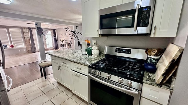 kitchen featuring stainless steel appliances, white cabinets, light stone counters, and ornamental molding