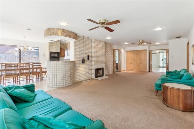 living room featuring a fireplace, light carpet, and ceiling fan with notable chandelier