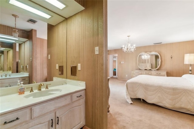 bathroom featuring a notable chandelier, wood walls, and vanity