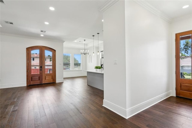 foyer with an inviting chandelier, dark hardwood / wood-style flooring, and ornamental molding