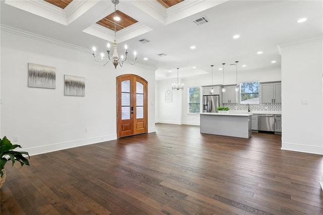 unfurnished living room featuring dark wood-type flooring, crown molding, coffered ceiling, and an inviting chandelier