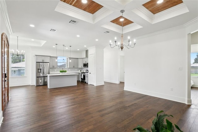 unfurnished living room featuring dark wood-type flooring, coffered ceiling, a chandelier, and crown molding