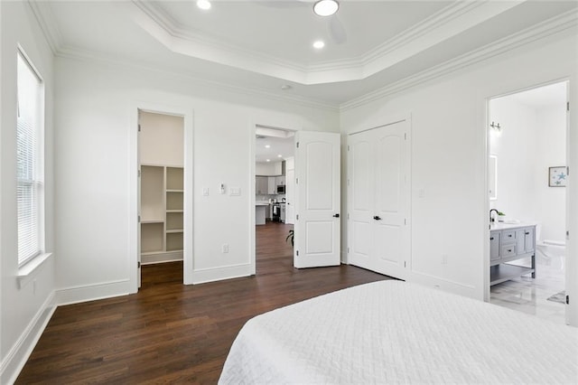 bedroom with a walk in closet, dark hardwood / wood-style floors, connected bathroom, and crown molding