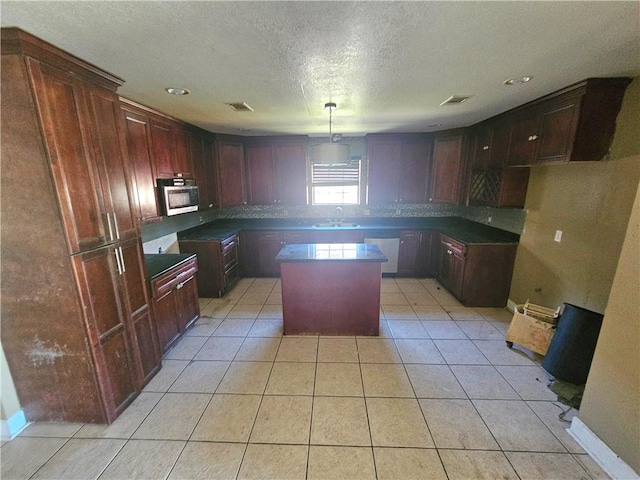 kitchen featuring appliances with stainless steel finishes, light tile patterned floors, decorative light fixtures, and a kitchen island