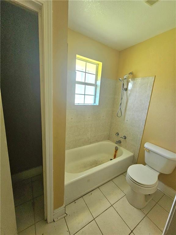 bathroom with tile patterned flooring, tiled shower / bath combo, and toilet