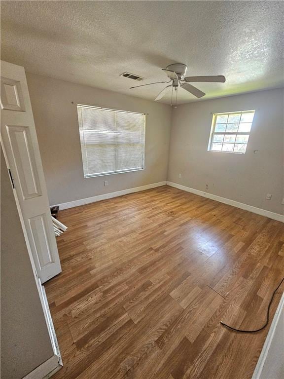 empty room featuring light wood-type flooring, a textured ceiling, and ceiling fan