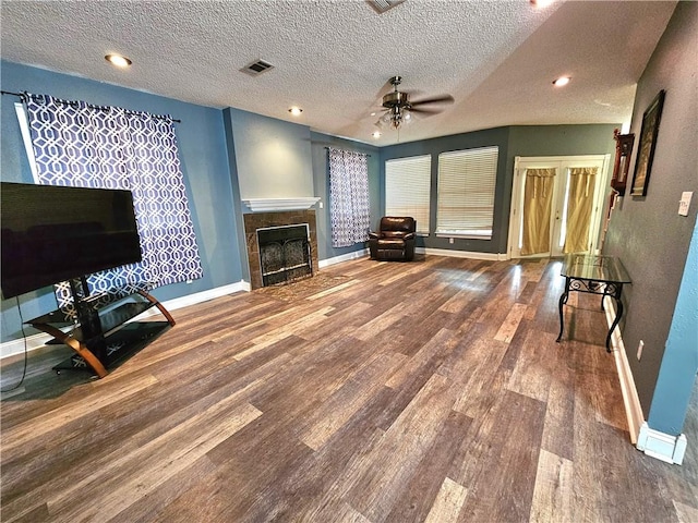 unfurnished living room featuring a textured ceiling, a fireplace, hardwood / wood-style flooring, and ceiling fan