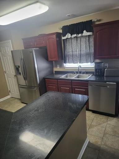 kitchen with stainless steel appliances, light tile patterned floors, and sink