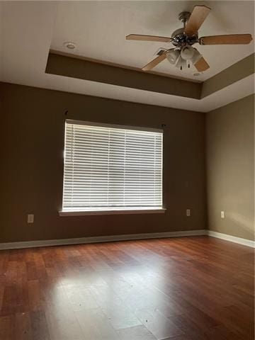 unfurnished room with hardwood / wood-style floors, plenty of natural light, and a tray ceiling