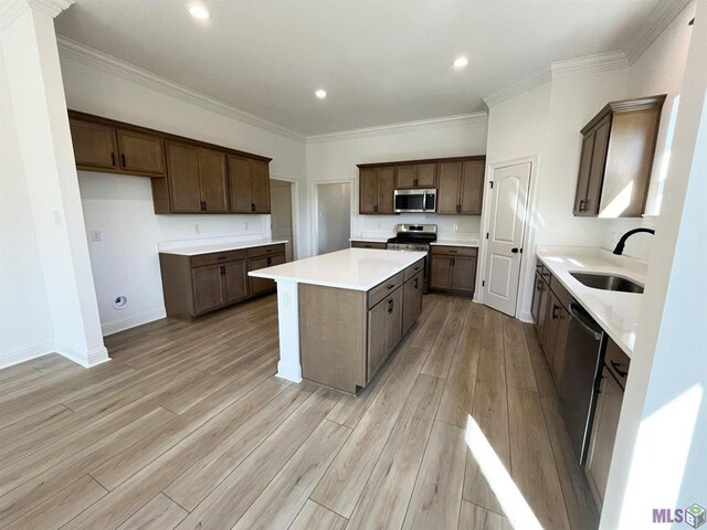 42401 Blue Bay Dr, Ponchatoula, LA 70454 - kitchen featuring appliances with stainless steel finishes, a sink, a kitchen island, light wood-type flooring, and ornamental molding