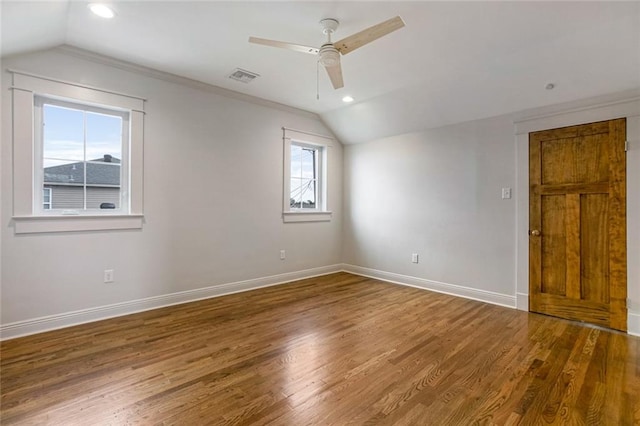 empty room featuring a healthy amount of sunlight, lofted ceiling, and wood-type flooring