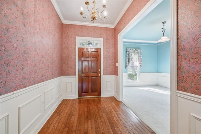 entryway featuring hardwood / wood-style flooring, crown molding, and an inviting chandelier