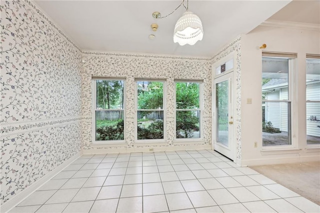 empty room featuring ornamental molding, a wealth of natural light, a chandelier, and light colored carpet