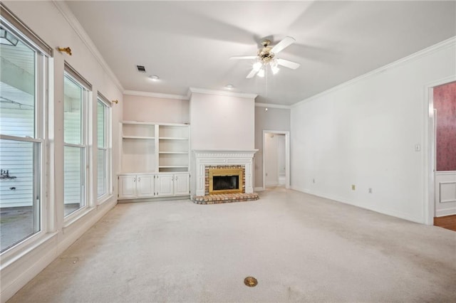 unfurnished living room featuring a fireplace, ceiling fan, crown molding, and light colored carpet