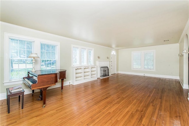 living room featuring built in shelves, wood-type flooring, and ornamental molding