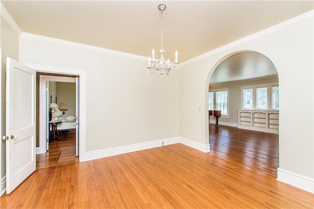 spare room featuring hardwood / wood-style flooring, ornamental molding, and a notable chandelier