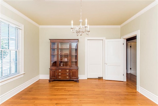 unfurnished dining area with light wood-type flooring, ornamental molding, and a notable chandelier