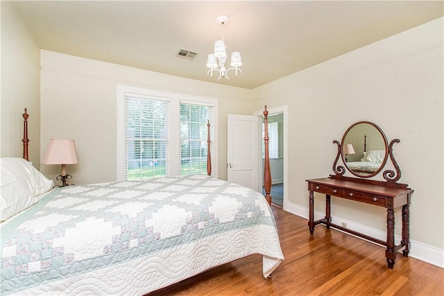 bedroom featuring an inviting chandelier and hardwood / wood-style flooring