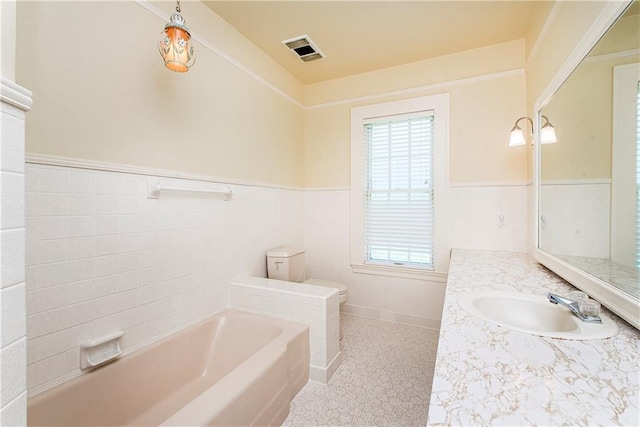 bathroom with a bathing tub, vanity, toilet, and tile walls