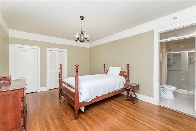 bedroom with ensuite bathroom, light wood-type flooring, and a chandelier