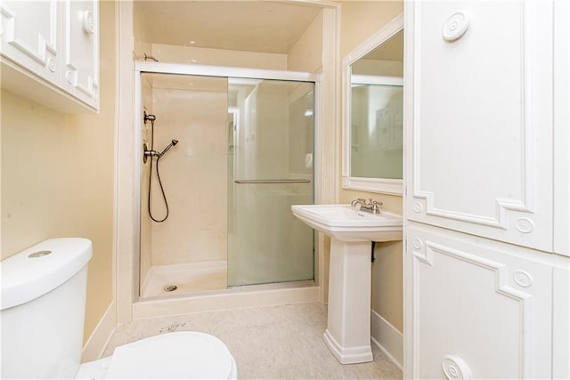 bathroom featuring toilet and a shower with door