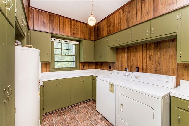 washroom with water heater, washer and clothes dryer, cabinets, and wooden walls