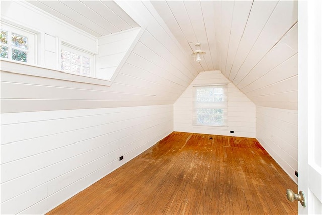 additional living space featuring hardwood / wood-style floors, vaulted ceiling, and wooden walls