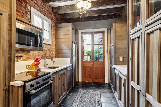 kitchen with beamed ceiling, a healthy amount of sunlight, sink, and appliances with stainless steel finishes