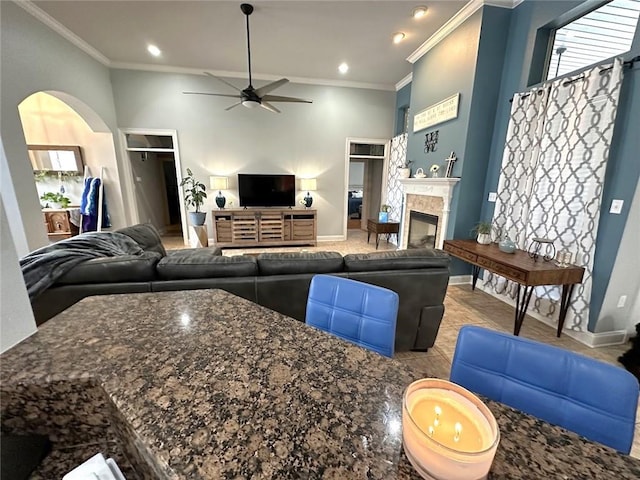 living room with ornamental molding, a towering ceiling, and ceiling fan