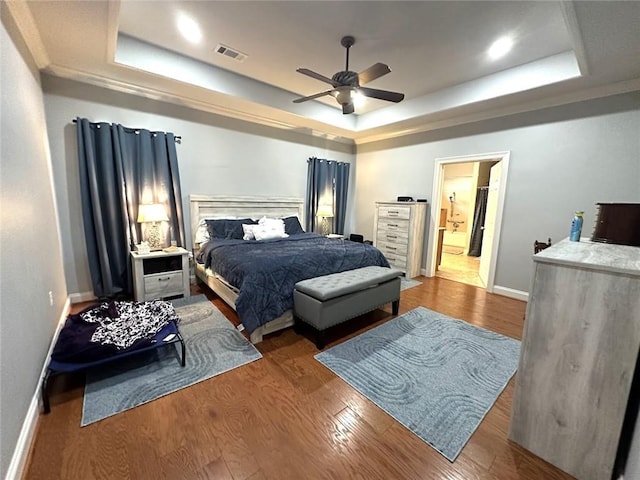 bedroom with wood-type flooring, ceiling fan, and a raised ceiling