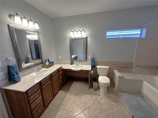 bathroom featuring toilet, tile patterned floors, tile walls, vanity, and a tub to relax in