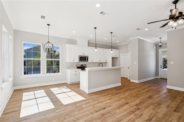 kitchen with stainless steel appliances, light hardwood / wood-style floors, decorative light fixtures, a kitchen island with sink, and white cabinets