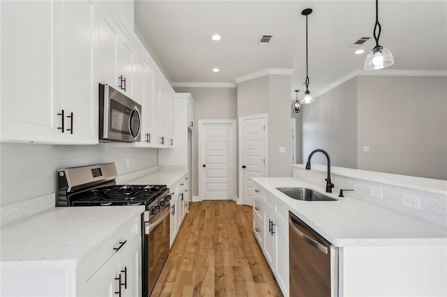 kitchen featuring sink, appliances with stainless steel finishes, decorative light fixtures, light hardwood / wood-style flooring, and white cabinets