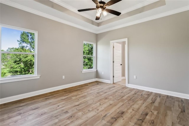 spare room featuring light hardwood / wood-style floors, ceiling fan, crown molding, and a tray ceiling