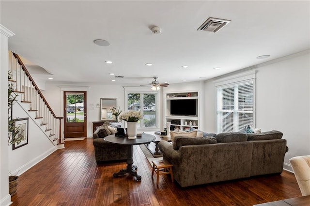 living room with ceiling fan, dark hardwood / wood-style floors, built in features, and crown molding