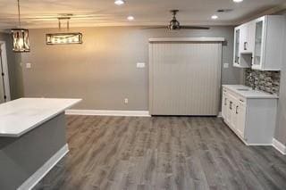 kitchen featuring ceiling fan, dark wood-type flooring, tasteful backsplash, decorative light fixtures, and white cabinets