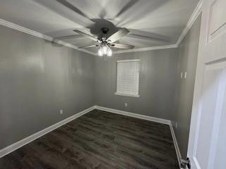 unfurnished room with crown molding, ceiling fan, and dark wood-type flooring