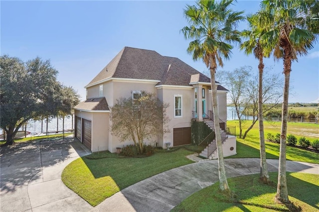 view of front of property featuring a garage, a water view, and a front yard