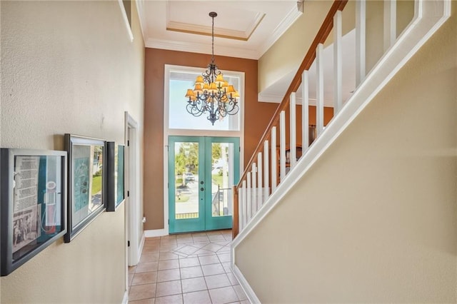 foyer featuring a chandelier, french doors, light tile patterned floors, and crown molding