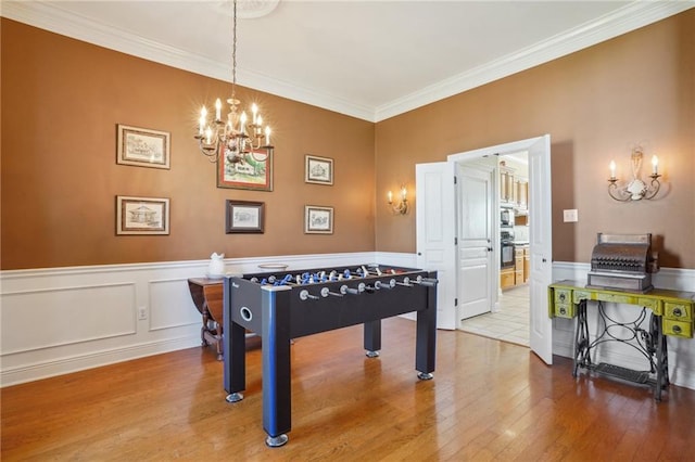 playroom with ornamental molding, hardwood / wood-style floors, and a notable chandelier