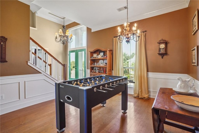 game room featuring hardwood / wood-style floors, a notable chandelier, french doors, and crown molding