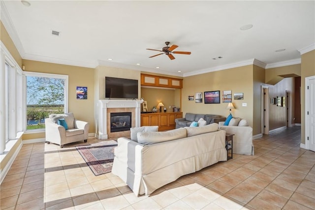 tiled living room featuring a fireplace, ceiling fan, and crown molding