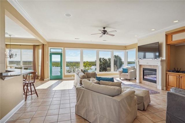 living room with a tiled fireplace, a healthy amount of sunlight, crown molding, and light tile patterned floors