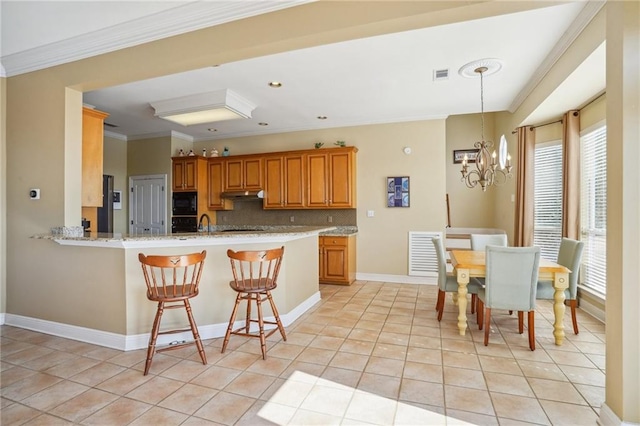 kitchen featuring a breakfast bar, kitchen peninsula, light tile patterned floors, a chandelier, and decorative backsplash