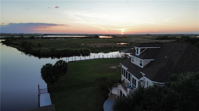 aerial view at dusk featuring a water view