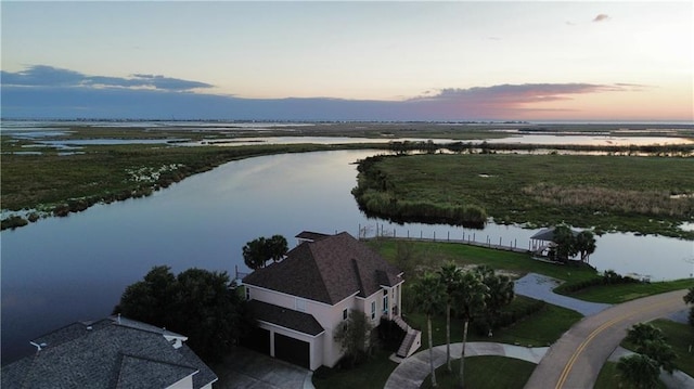 aerial view at dusk featuring a water view