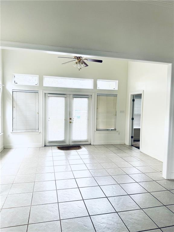 unfurnished room with ornamental molding, a ceiling fan, french doors, and light tile patterned floors